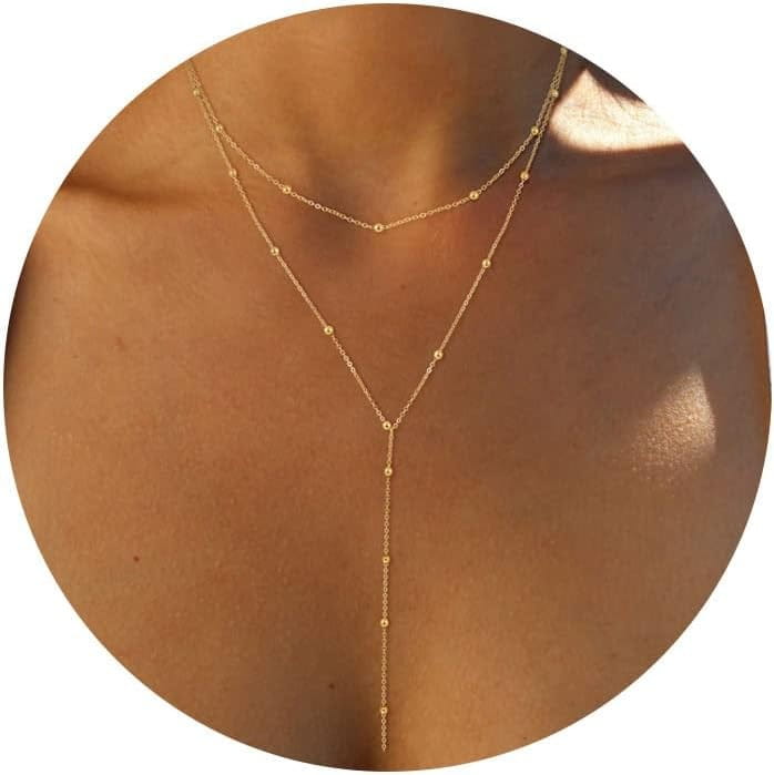 Un collier en « y » à superpositions délicates à tonalité dorée, pour femmes, présentant de petites perles sphériques le long des chaînes.
