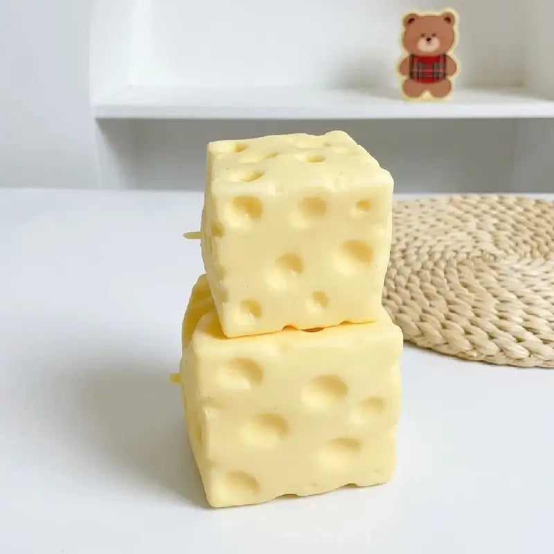 Zwei hellgelbe, würfelförmige Käse-Seifenstücke mit charakteristischen Löchern, entworfen als Käse-Soft-Glücksbringer-Spielzeuge zur Stressreduktion.