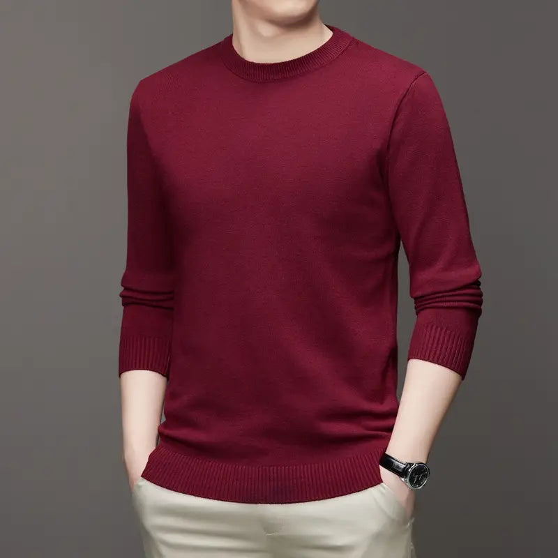 Ein klassischer Herren-Strickpullover mit Rundhalsausschnitt aus sattem Burgund mit langen Ärmeln sowie geripptem Rundhalsausschnitt und Bündchen aus Strickmaterial.