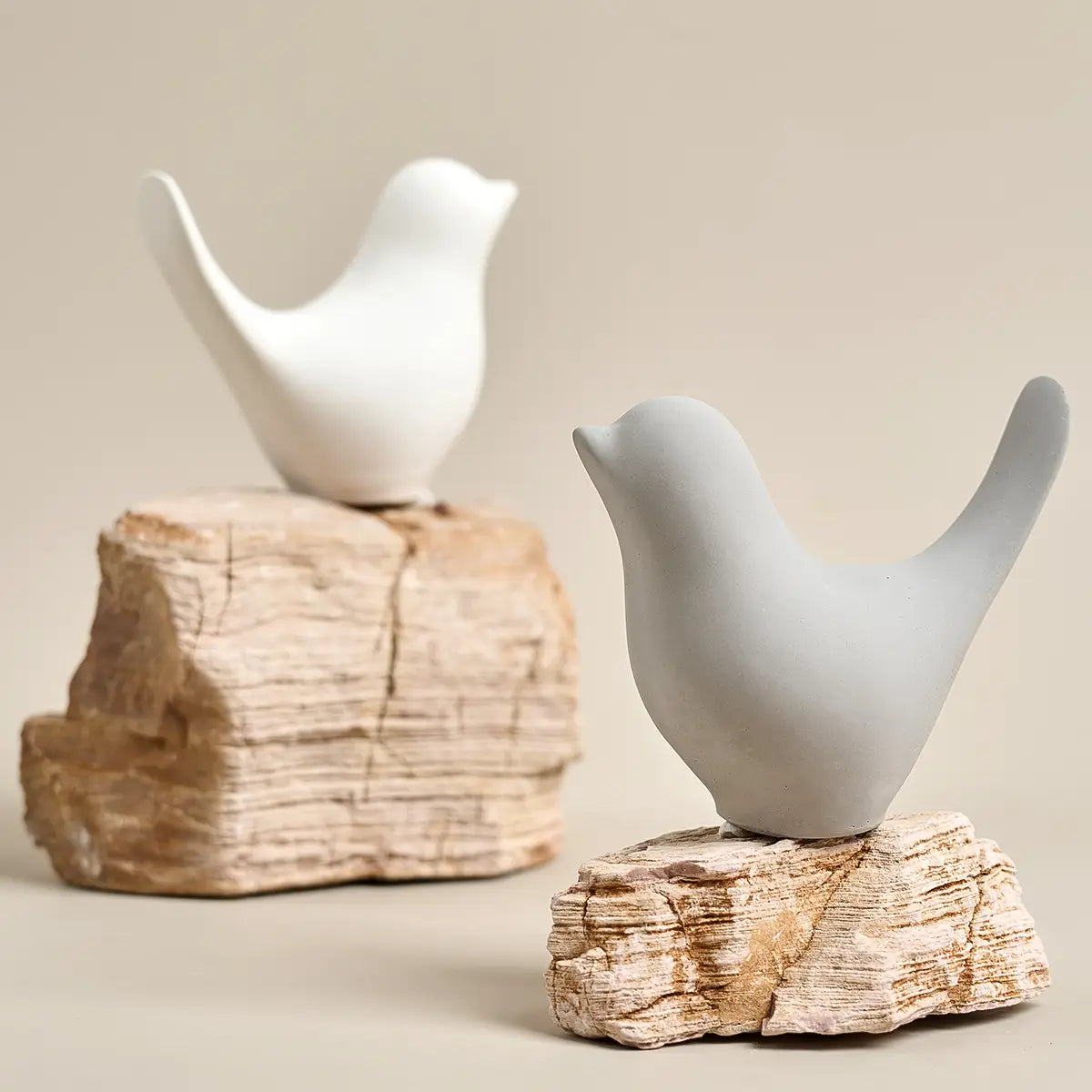 weiße Keramikfigur eines Vogels mit glattem, minimalistischen Design, die auf einer strukturierten Steinbasis ruht, hergestellt mit Gipsformguss-Pulver für DIY-Bastelarbeiten