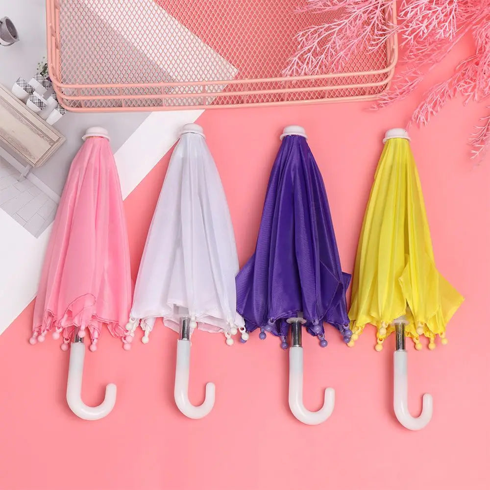 four colorful mini doll umbrellas bjd accessories with white curved handles and pom-pom trim on fabric canopies