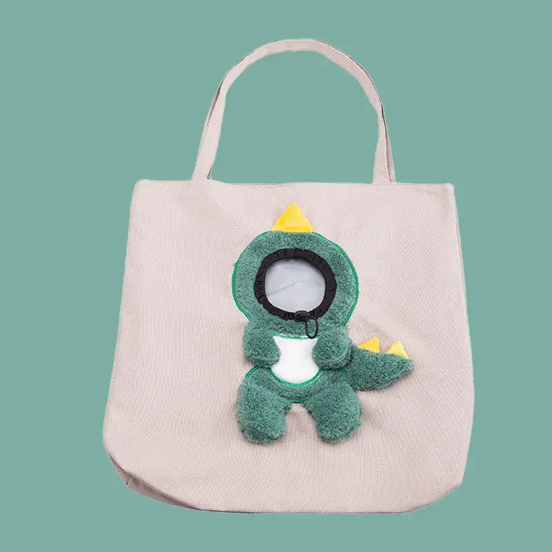 a soft green plush dinosaur with yellow spikes and a white belly attached to a beige canvas carrier bag designed for small dog and cat use with a mouth length opening