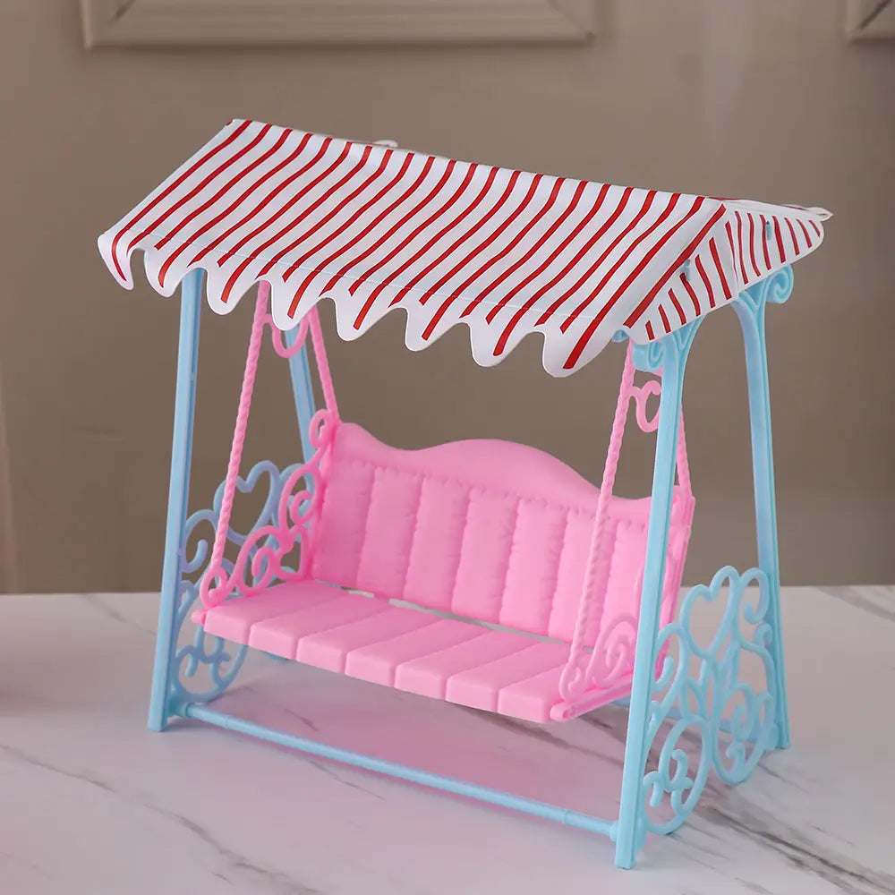 Rosa und hellblaue Kunststoff-Puppenhaus-Schaukel mit einem rot-weiß gestreiften Baldachin aus dem Puppenhaus-Miniaturmöbel-Wohnraumdekoration-Set.