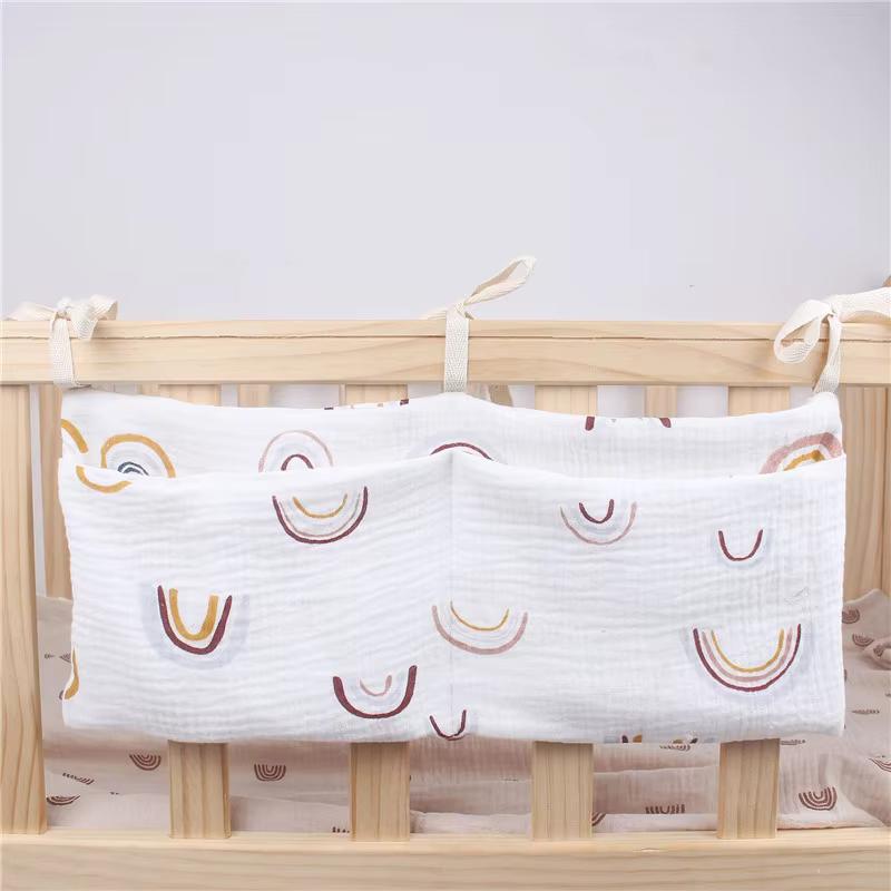 Weiße Baumwollstoff-Babyliege-Organizer-Aufbewahrungstasche mit zwei Taschen mit einem verspielten Muster aus Regenbogenbögen in sanftem Gold und gedämpften Brauntönen für eine Wickeltisch-Aufbewahrungstasche zur Windelorganisation.