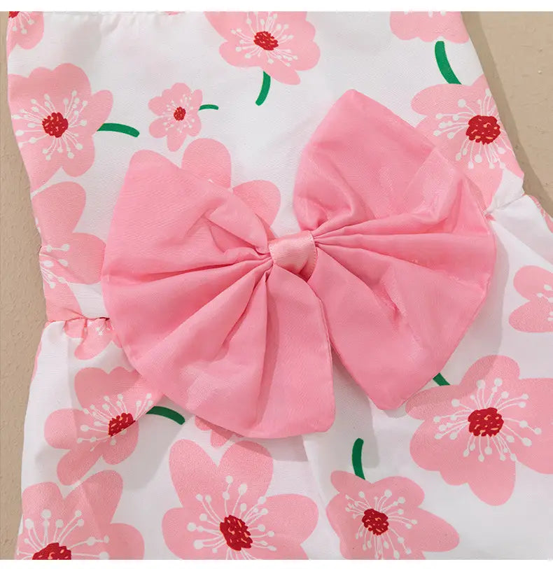 a floral dog princess dress with a large soft pink fabric bow and printed cherry blossoms on white material