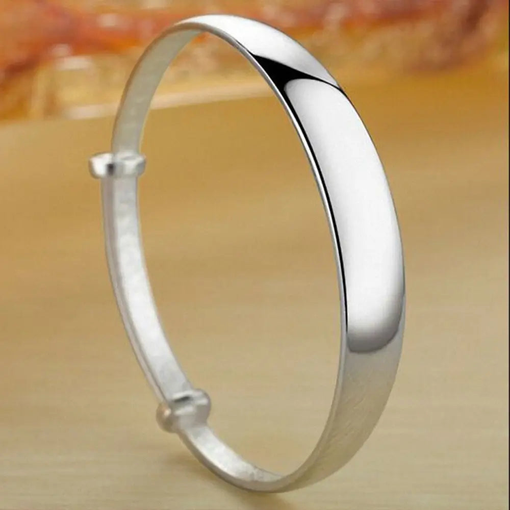 Sterling silver round bangle bracelet for women featuring a sleek minimalist design with a smooth polished finish and adjustable clasp.