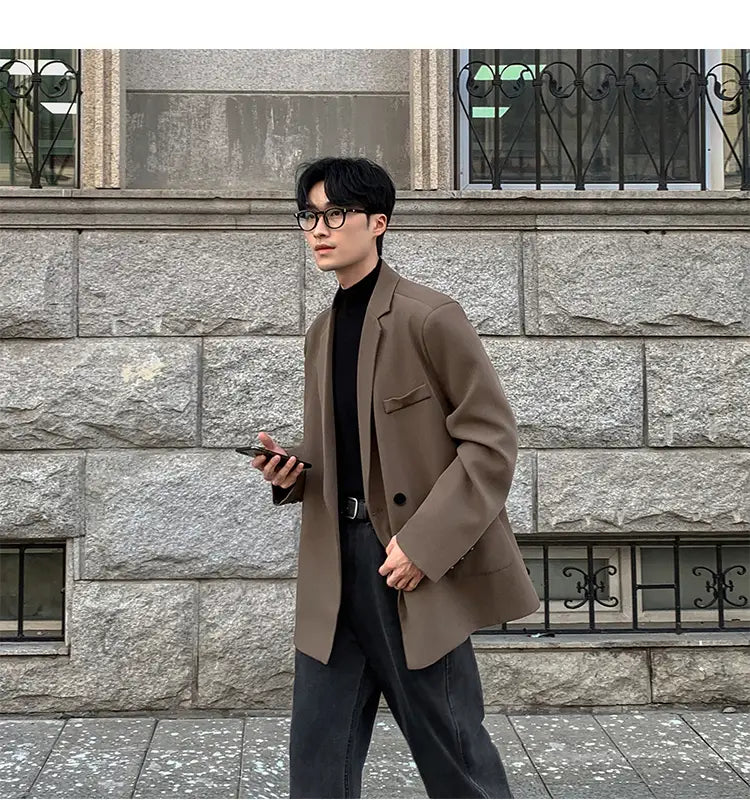 Una blazer de doble botonadura casual para hombre de chaqueta de traje de poliéster en color marrón, con ajuste relajado, que presenta botones negros y bolsillos tipo cartera con solapa sutiles.