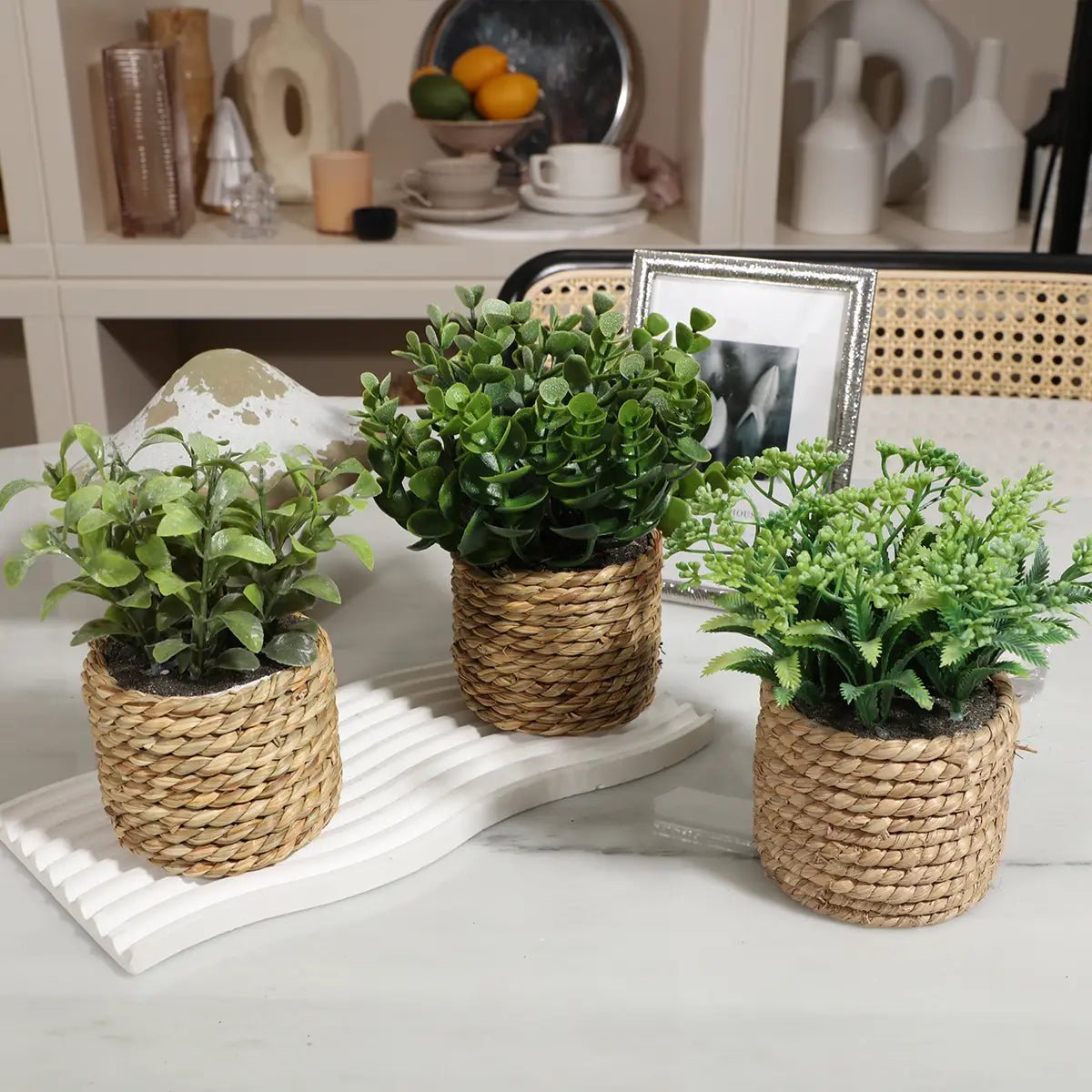 Three small woven rattan planters with lush green artificial eucalyptus flowers as small potted plants measuring 17cm.