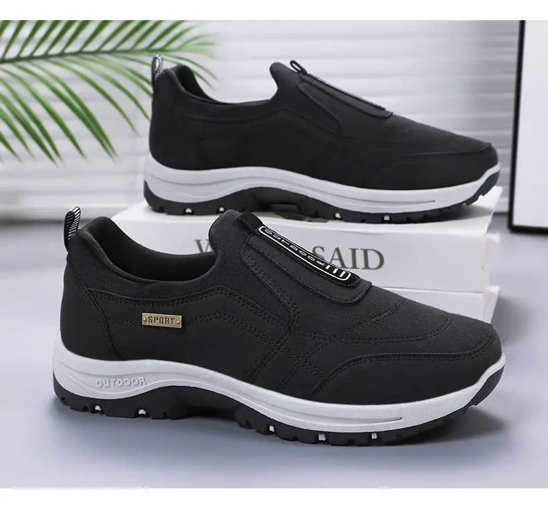 Men orthopedic slip-on walking shoes in black with a textured upper, white rubber sole, and sport branding on the side.