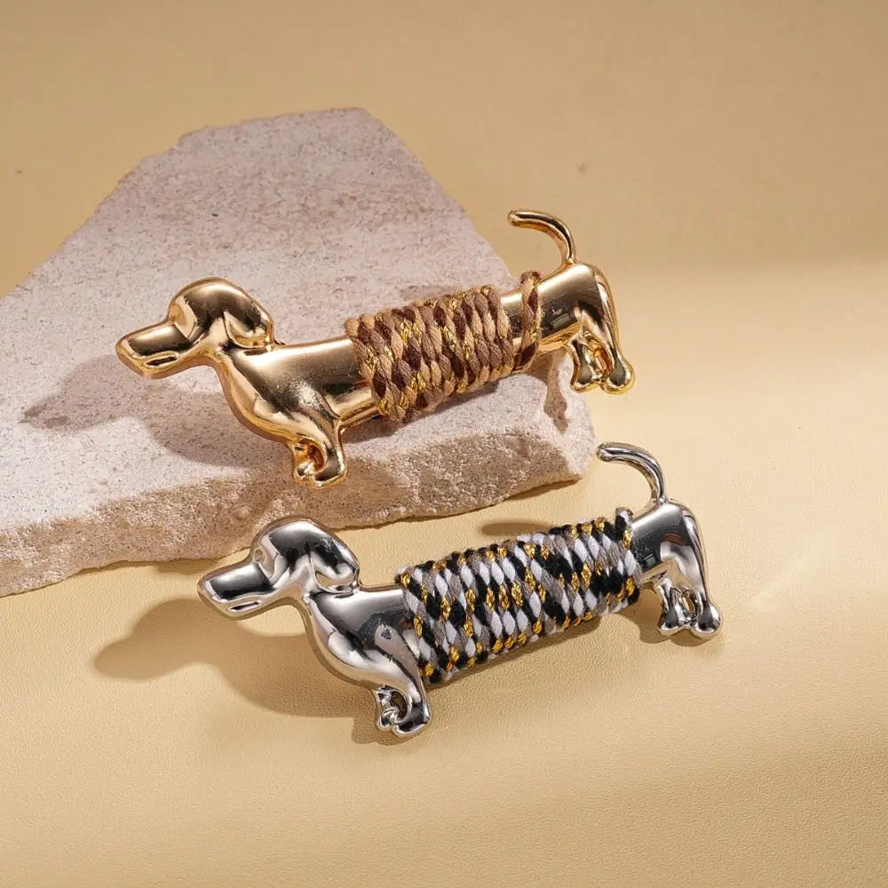 les broches en forme de teckel en or et en argent, avec un détail en corde tressée, sont des broches à revers animalières en métal, conçues pour agrémenter élégamment vos accessoires.