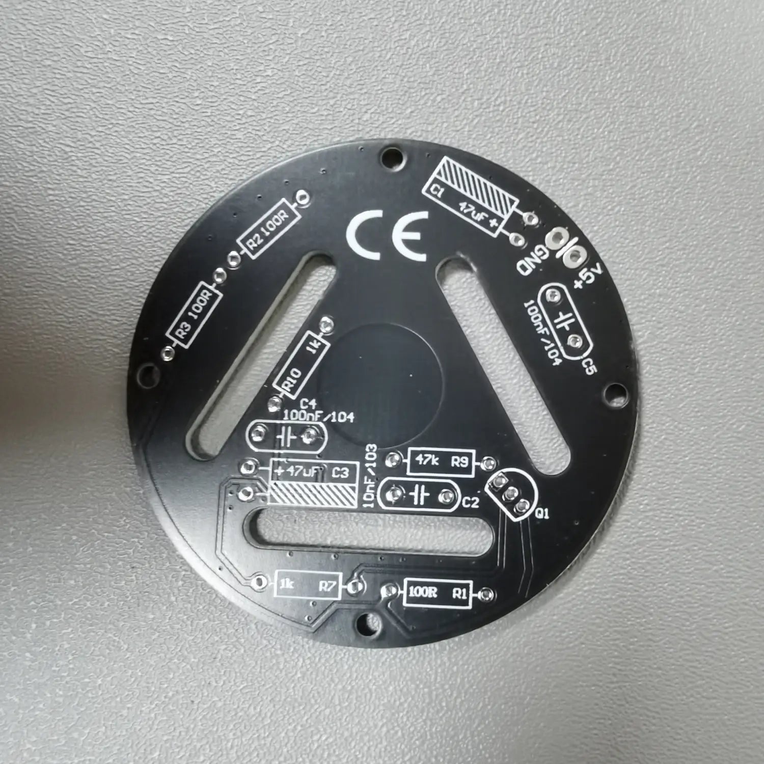 placa de circuito impreso circular negra con marcas de componentes grabadas en blanco y orificios de montaje para el kit de soldadura DIY de LED regulables mediante contacto.