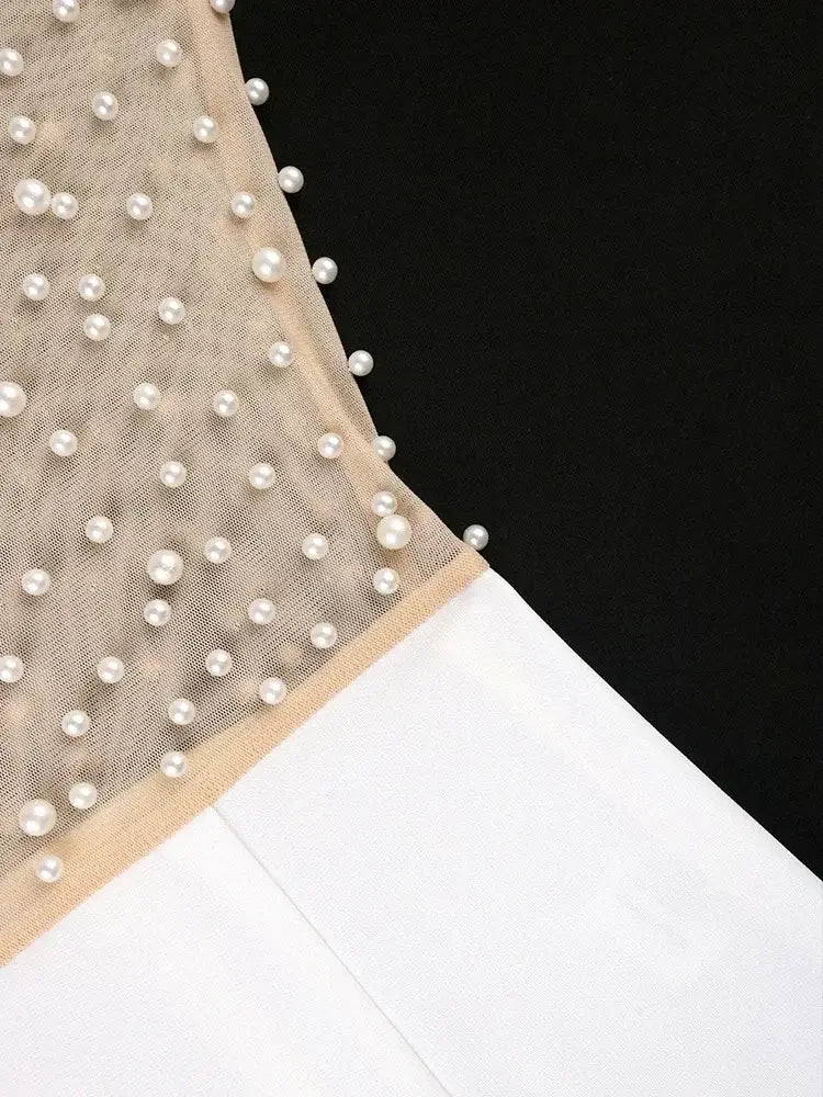 beige sheer fabric adorned with evenly spaced white pearls along the edge of a beaded high waisted jumpsuit elegant party outfit