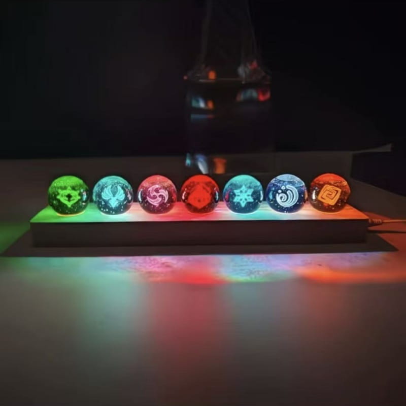 Sept sphères de verre translucides et lumineuses, avec des motifs gravés complexes dans des couleurs vibrantes, affichées sur une base éclairée comme produits finis de la boule de cristal de Genshin Impact.