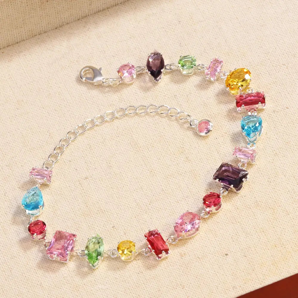 A colorful zircon crystal bracelet featuring a silver chain and assorted faceted stones in pink red yellow green blue and purple.