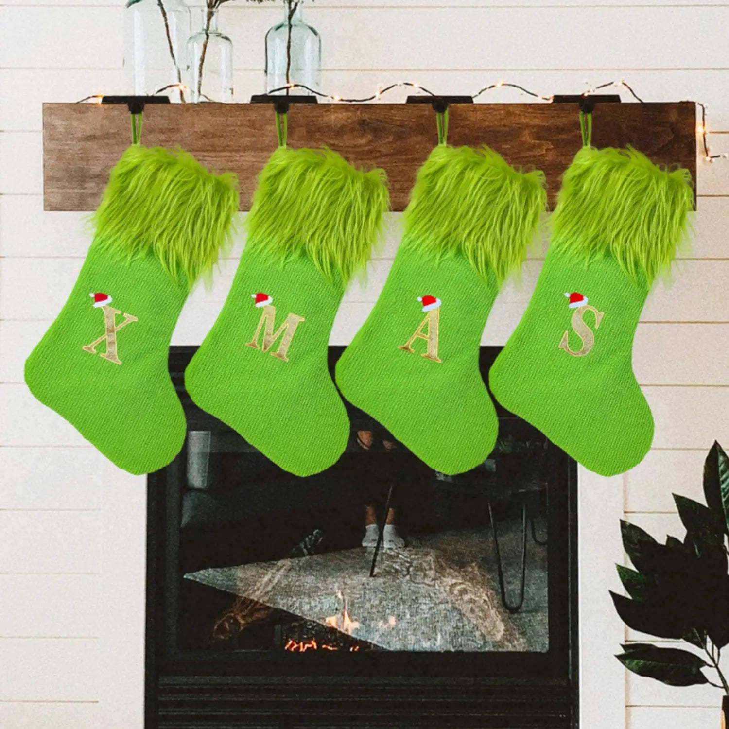 Four bright green fuzzy christmas stockings with gold embroidered letters spelling xmas and small santa hats above each letter in a green monogrammed christmas stocking with santa hat product.