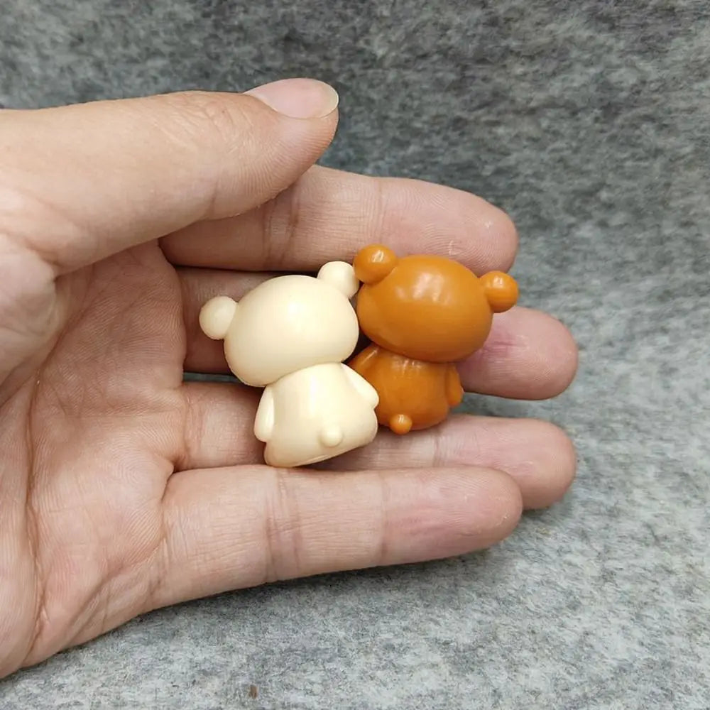 Two small glossy plastic Rilakkuma bear keychain figurines in cream and orange colors resting in the palm of a hand as cute DIY pendants.