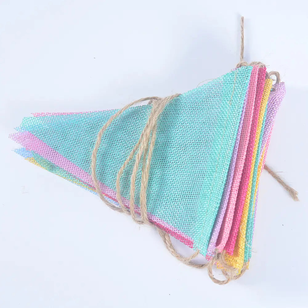 Décoration de guirlande de fête en feutrine pastel, présentant une guirlande en forme de triangle en toile de jute aux couleurs pastel, suspendue avec une ficelle naturelle.
