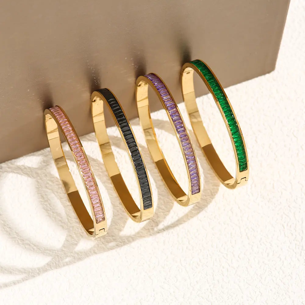 Set aus Armreif aus rostfreiem Stahl in Goldtönung mit Kristallen, mit leuchtenden rechteckig geschliffenen Edelsteinen in Pink, Schwarz, Violett und Grün.