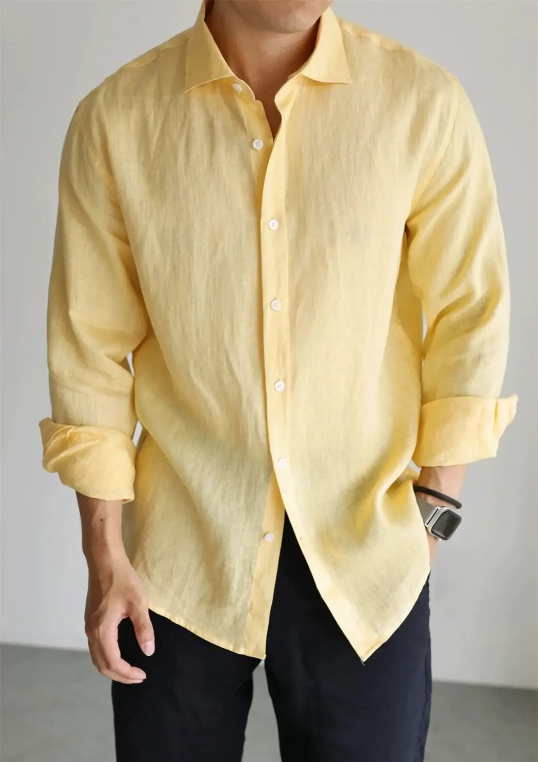 Men cotton linen casual button down shirt in pale yellow made of lightweight fabric with long sleeves and rolled cuffs.
