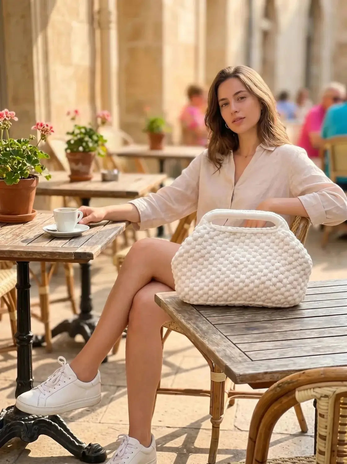 Un bolso bandolera tejido a crochet con textura de tejido blanco, elaborado con material ligero, adecuado para su uso como bolso para vacaciones de playa.