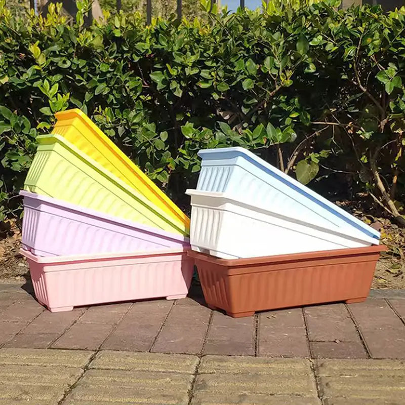 Macetas rectangulares de plantación apiladas en tonos pastel y terrosos con lados acanalados, para exhibición versátil de plantas y uso en jardinería.