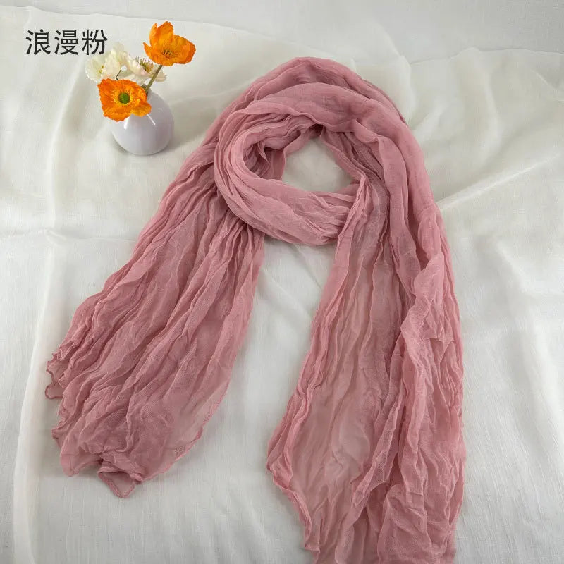 Écharpe en coton et lin plissé rose poudré doux, avec une texture de mousseline de chiffon légère et fluide et de délicates ondulations.