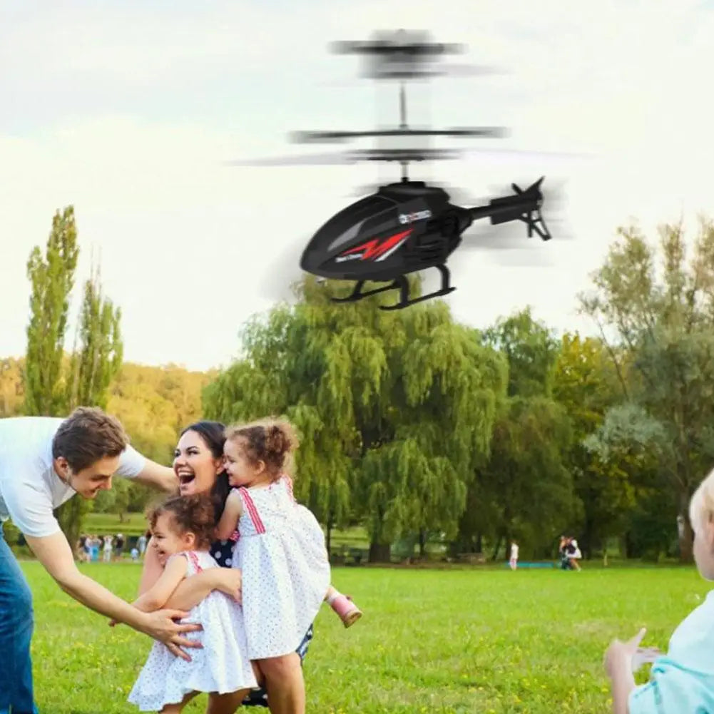 Black remote control induction suspension helicopter toy with red and white accents flying above a family in a park.