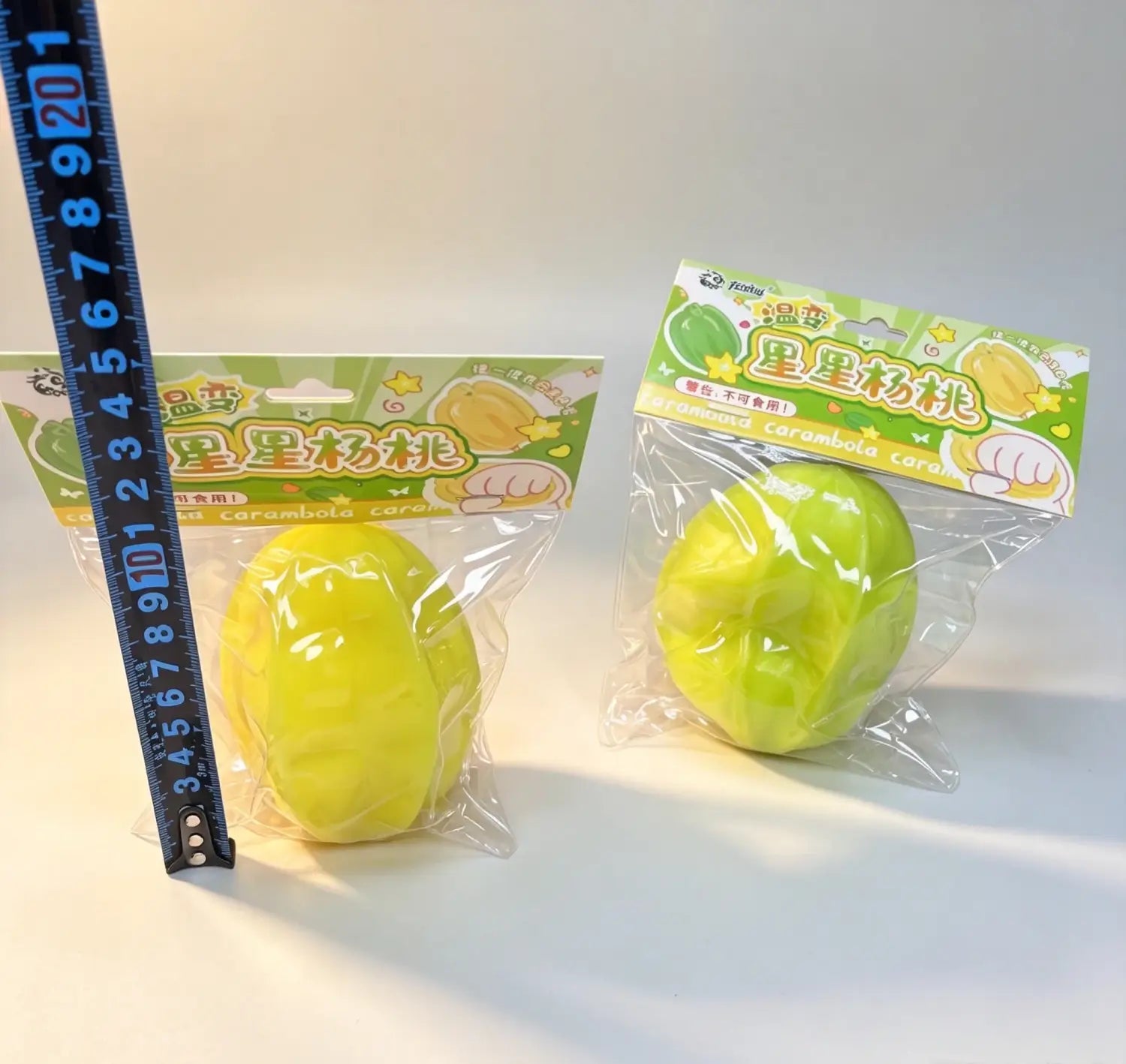 Juguete blando de fruta estrella que cambia de temperatura con forma de estrella de caramelo blando color amarillo verdoso brillante, envasado en plástico transparente.