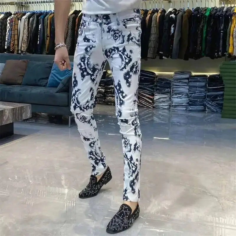 Men black floral slim fit jeans in white denim featuring a bold black floral pattern paired with matching embellished loafers.