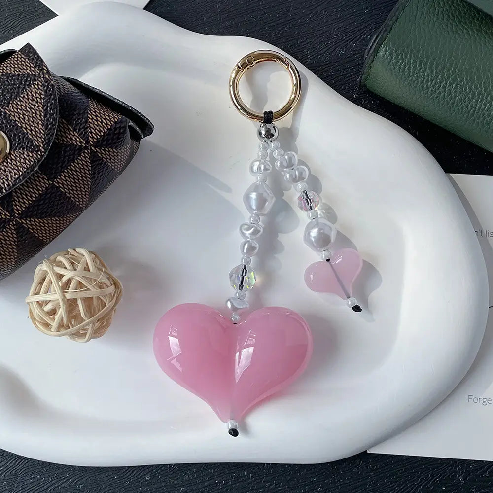 Porte-clés en forme de cœur rose, pendentif pour sac à perles, finition brillante orné de perles transparentes et de perles à l’aspect perlé, fixé à un anneau à finition dorée.