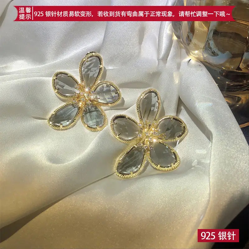 透明のファセットカットクリスタル花びらと、繊細なビーズ仕上げの縁を備えた、金色調の金属のゴールドフラワークリスタルスタッドピアス。