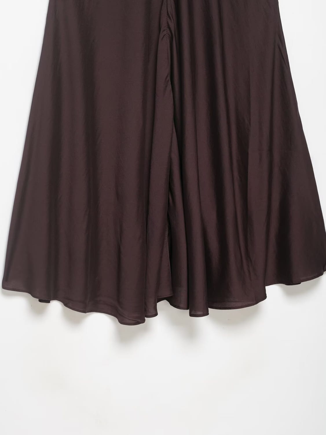 Ein fließender dunkelbrauner Satin-Plisseerock im Midi-Format mit hoher Taille und glattem, leichtem Material in einer A-Linien-Silhouette.