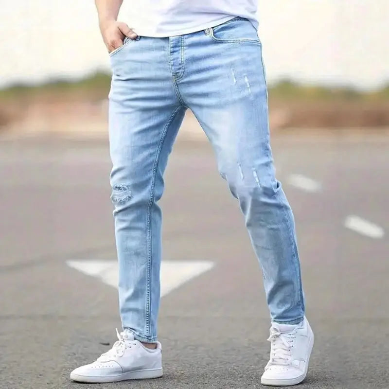 Men distressed skinny jeans in light-wash denim with ripped details on the knees and thighs designed for a vintage slim fit.