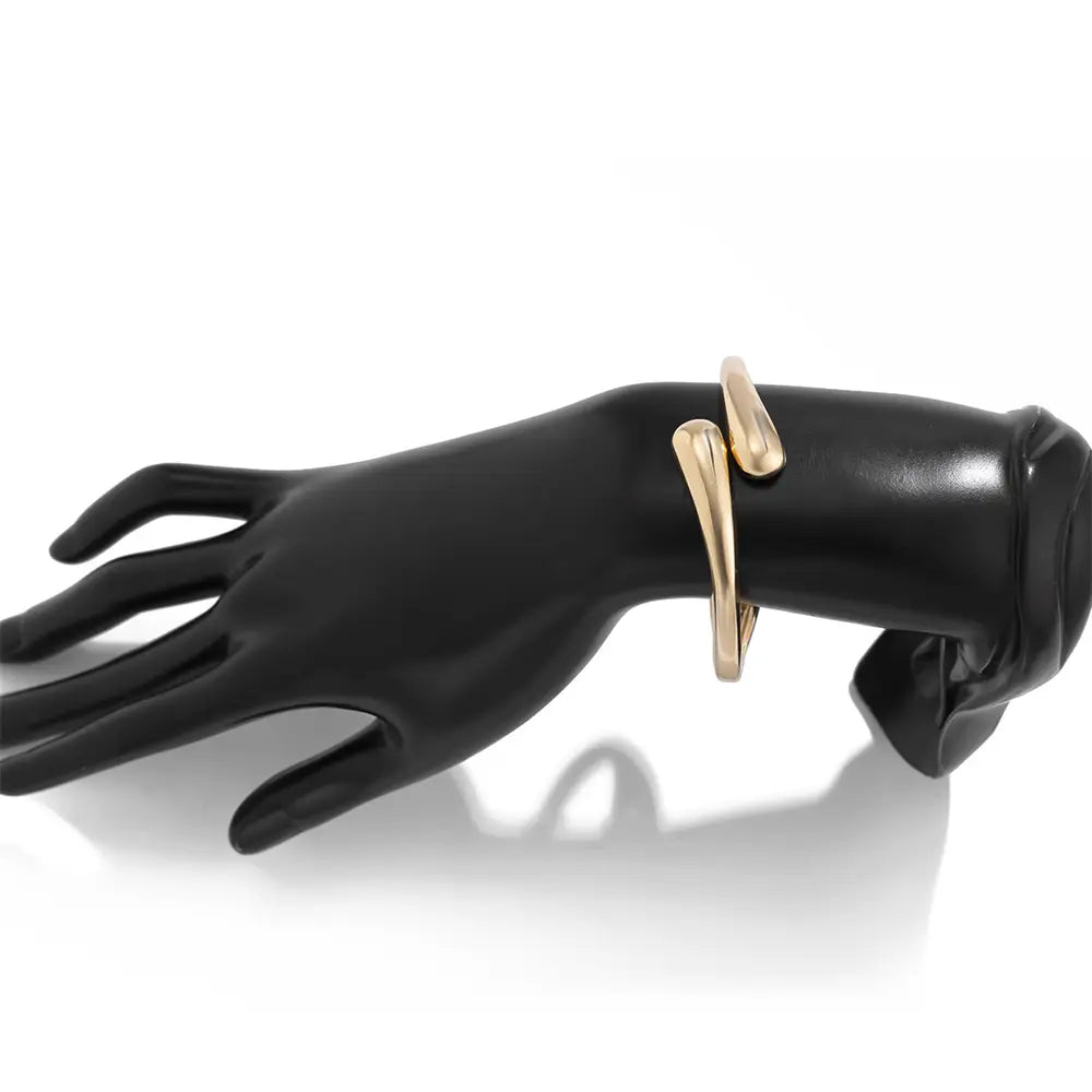 wide metal bangle featuring a gold-toned sleek and minimalist design with a modern curved open cuff style.