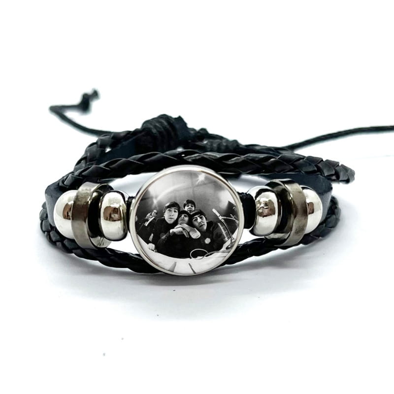 beatles leather braided bracelet featuring black braided leather with silver-toned metal beads and a circular glass dome charm displaying a black and white photo of the Beatles.