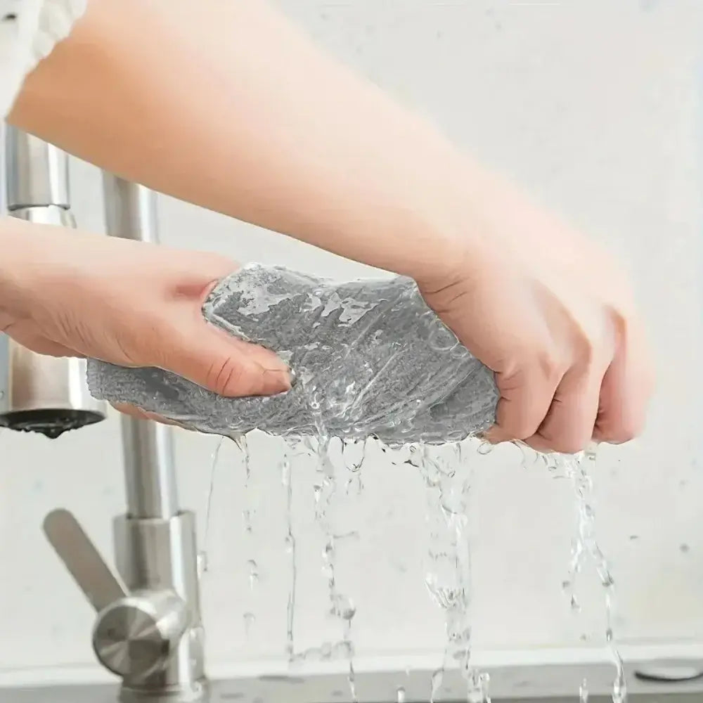 Éponge en maille grise provenant d’un ensemble de chiffons de nettoyage en microfibres et d’essuie-tout absorbants, rincée sous l’eau courante
