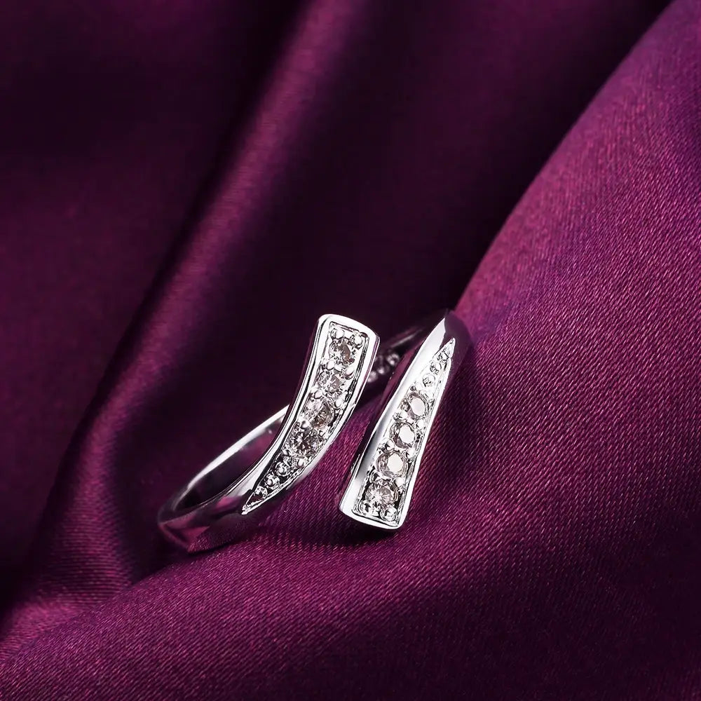 Offener, verstellbarer Silberring aus 18k Gold für Damen mit einem eleganten, modernen Design: zwei geschwungene Bänder, die mit klaren kubischen Zirkonia-Steinen besetzt sind, gesetzt in einem anmutigen, linearen Muster.