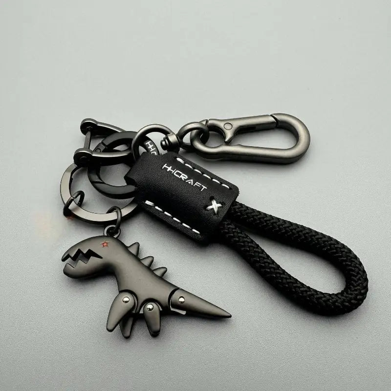 llavero de cuero con forma de dinosaurio negro trenzado, con detalles cosidos y herrajes metálicos, diseñado como llavero metálico.