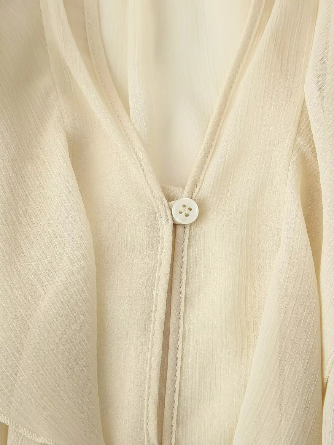 a delicate off-white chiffon ruffle shirt long sleeve with a subtle ribbed texture and a single white button at the neckline