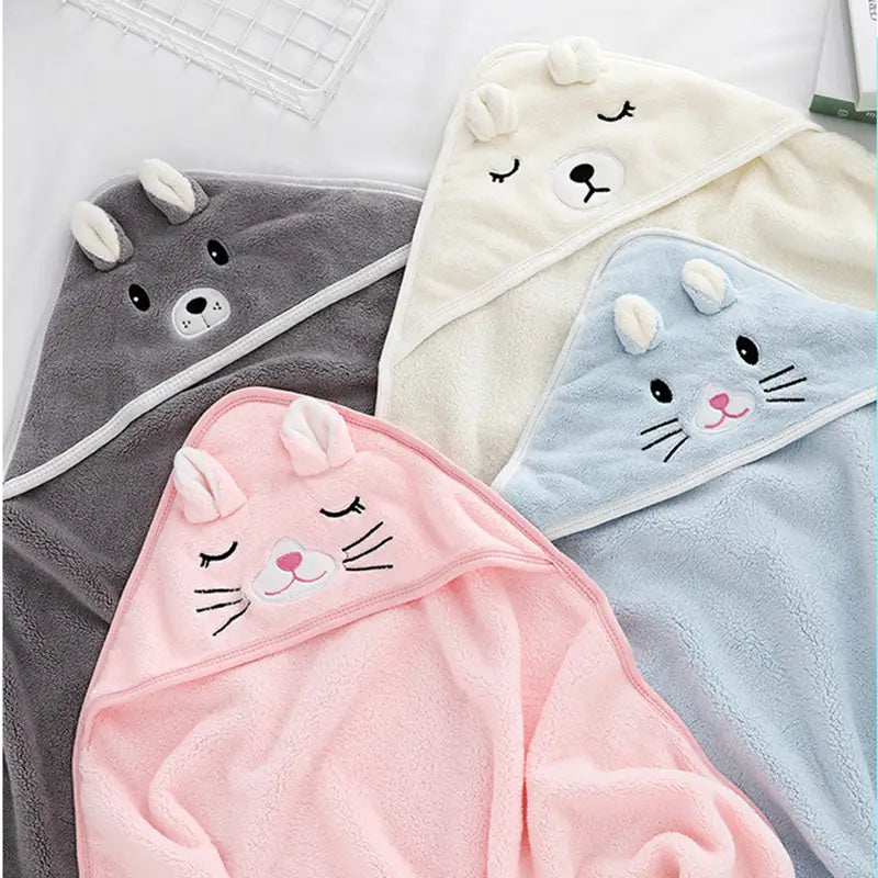 Baby-Bademantel- und Handtuch-Set mit Kuscheltier, mit Kapuze, bestehend aus weichen, plüschigen Kapuzenhandtüchern in Grau, Creme, Hellblau und Pink mit bestickten Tiergesichtern, geschlossenen Augen und angenähten Schnurrhaaren.