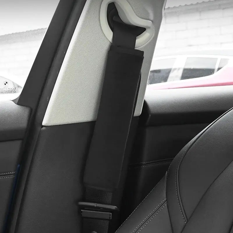 Black fabric plush seat belt cover with white plastic buckle attachment for car shoulder pads.
