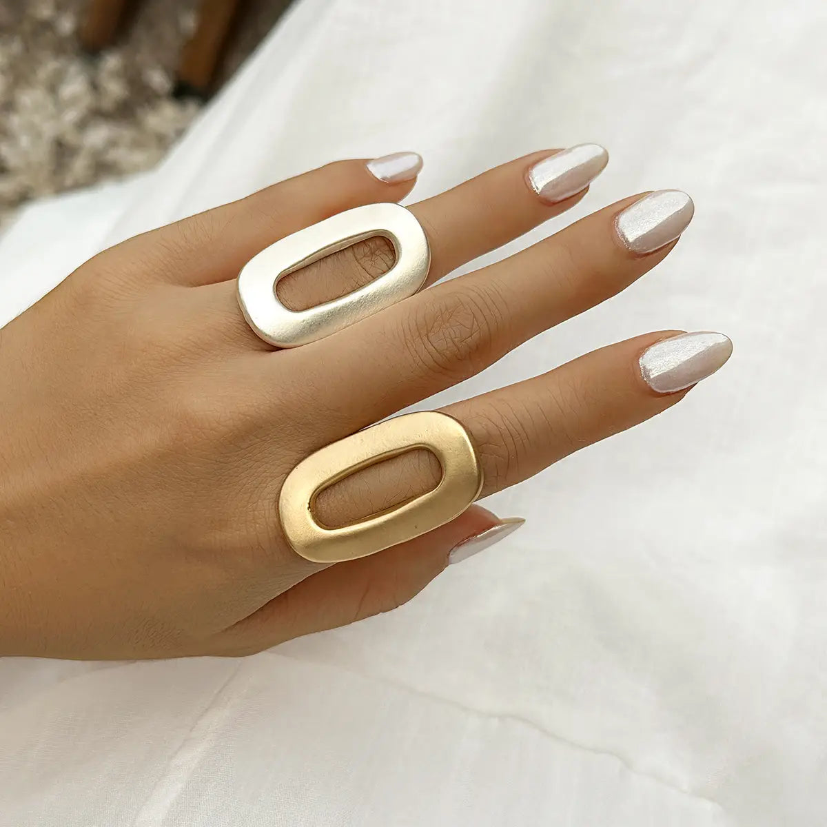 Two statement geometric oval open rings for women in silver and gold with a sleek metallic finish and an open center design.
