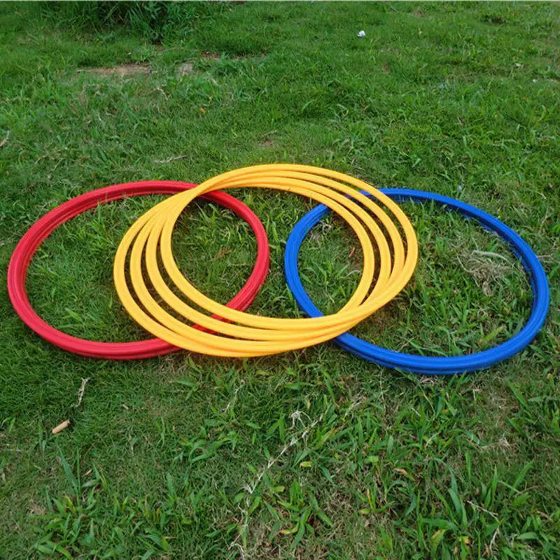 Three brightly colored red yellow and blue plastic agility training rings arranged overlapping on green grass for soccer speed exercise equipment.