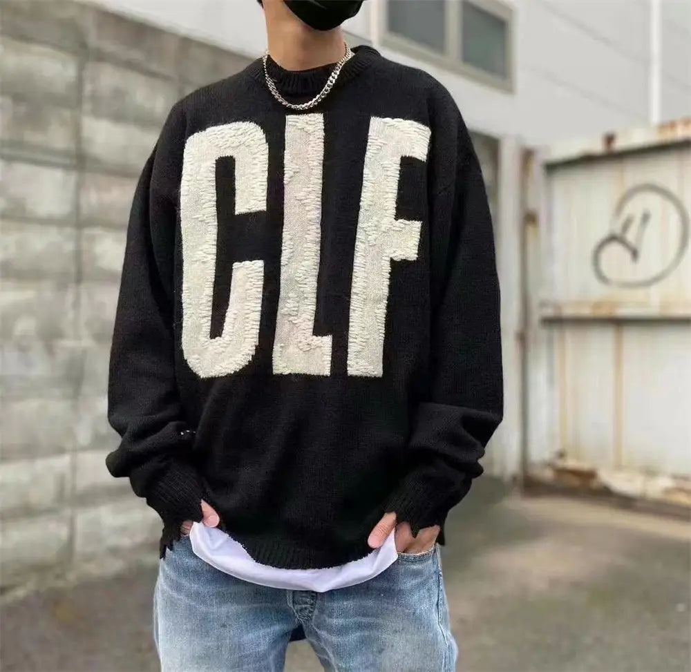 sin刺繍コレクションの、テクスチャのあるフワフワ素材でオーバーサイズの白い「clf」レタリングをあしらったブラックニットセーター。
