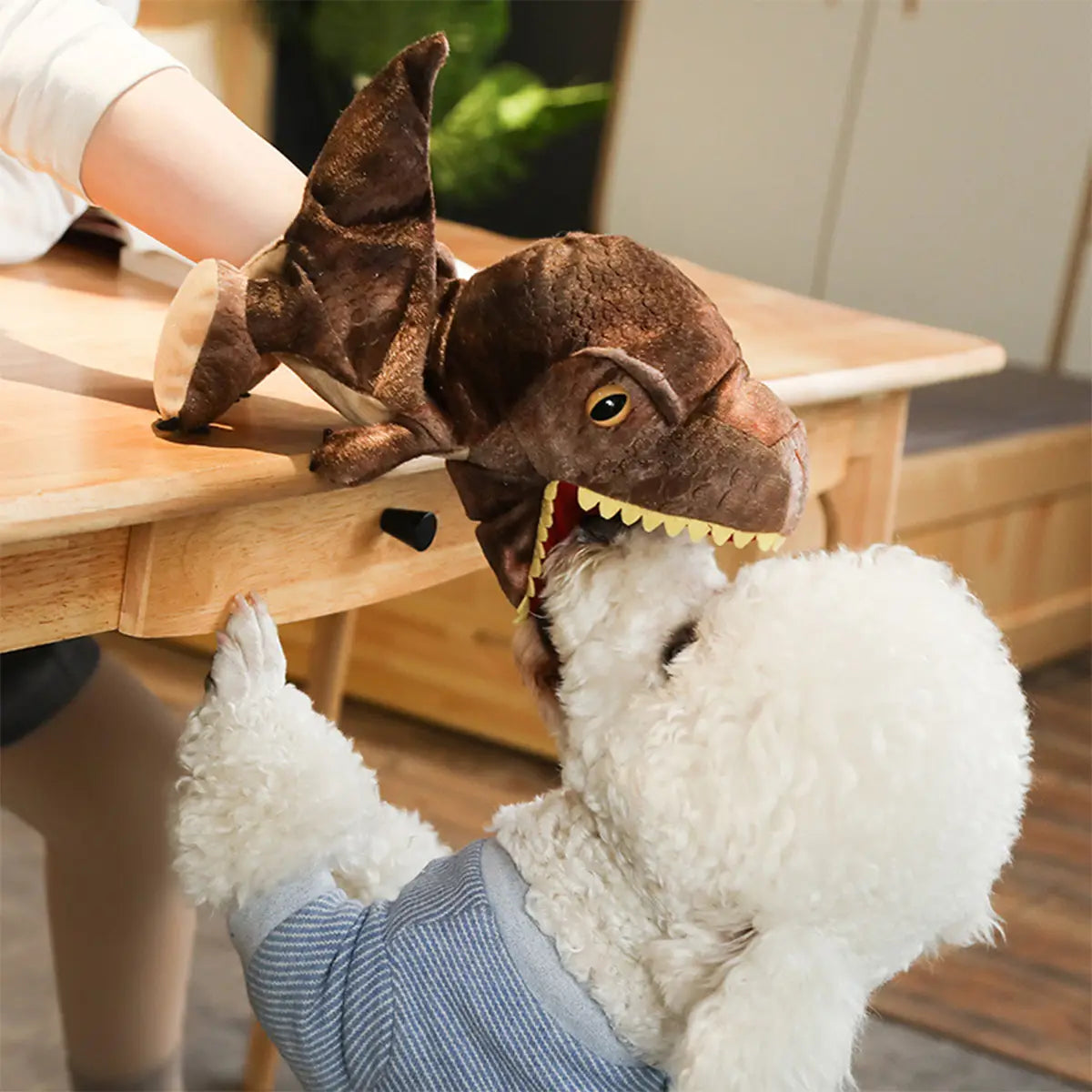 白いトイプードルに身に着けさせる茶色のぬいぐるみ恐竜の手人形で、黄色い歯と黒い目を備えたインタラクティブなおもちゃ。