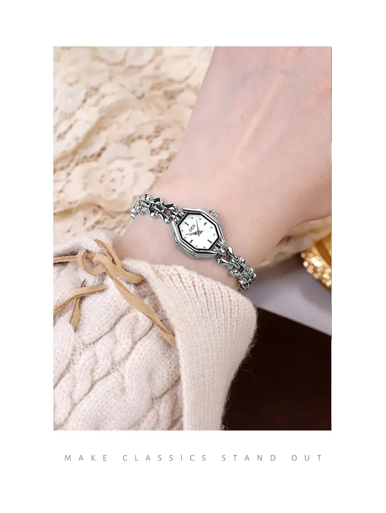 silver-toned octagonal ladies luxury quartz watch with white dial and intricate linked bracelet worn on wrist