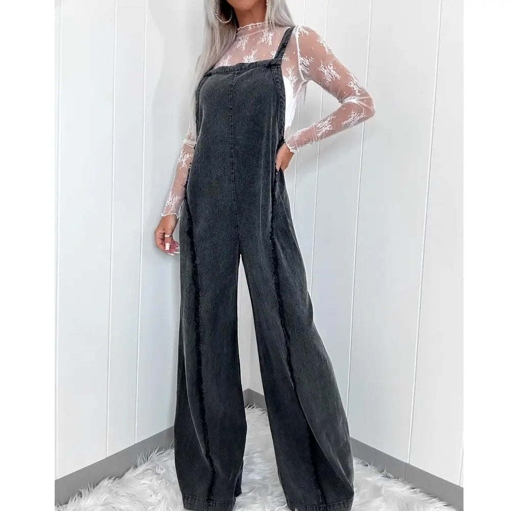 women wide leg denim jumpsuit in black denim paired with a sheer lace top showcasing a vintage long overall style.
