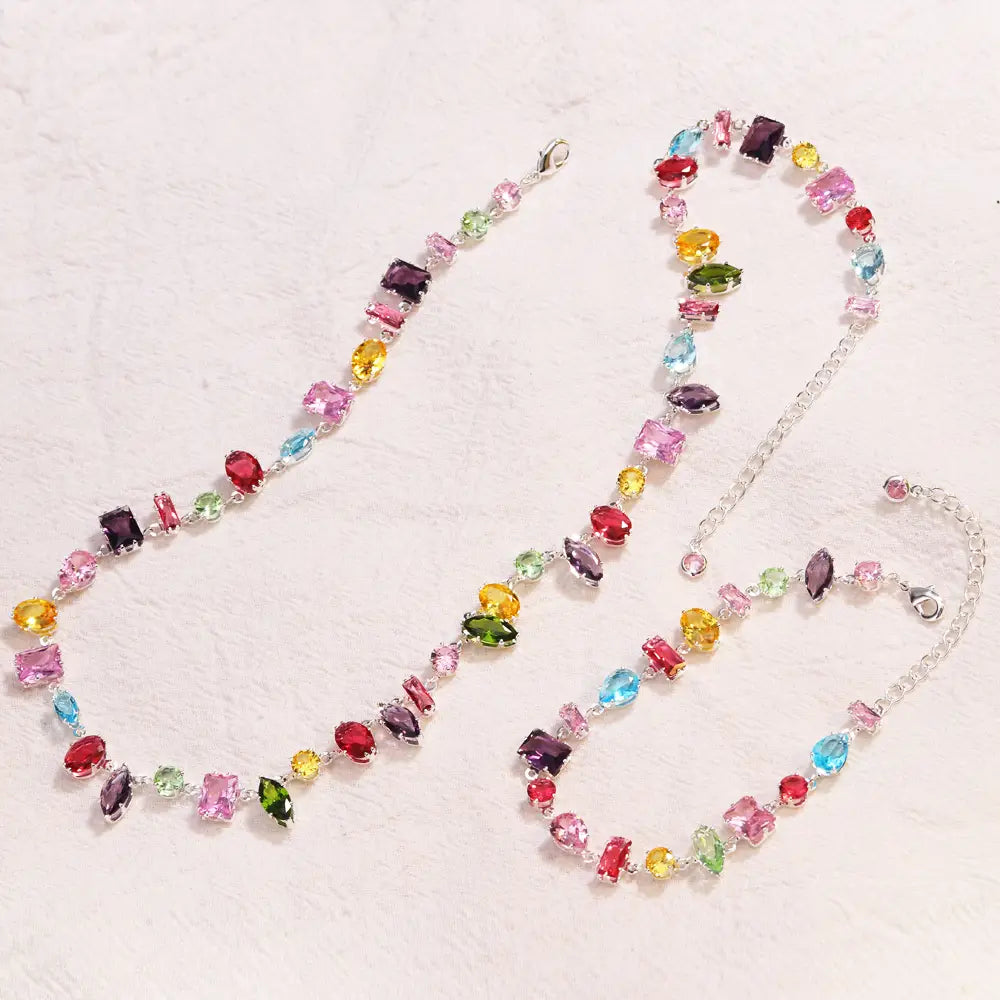 A colorful zircon crystal gold plated necklace featuring a silver chain with multi-colored rectangular and oval-cut gemstones in shades of pink red yellow green blue and purple.