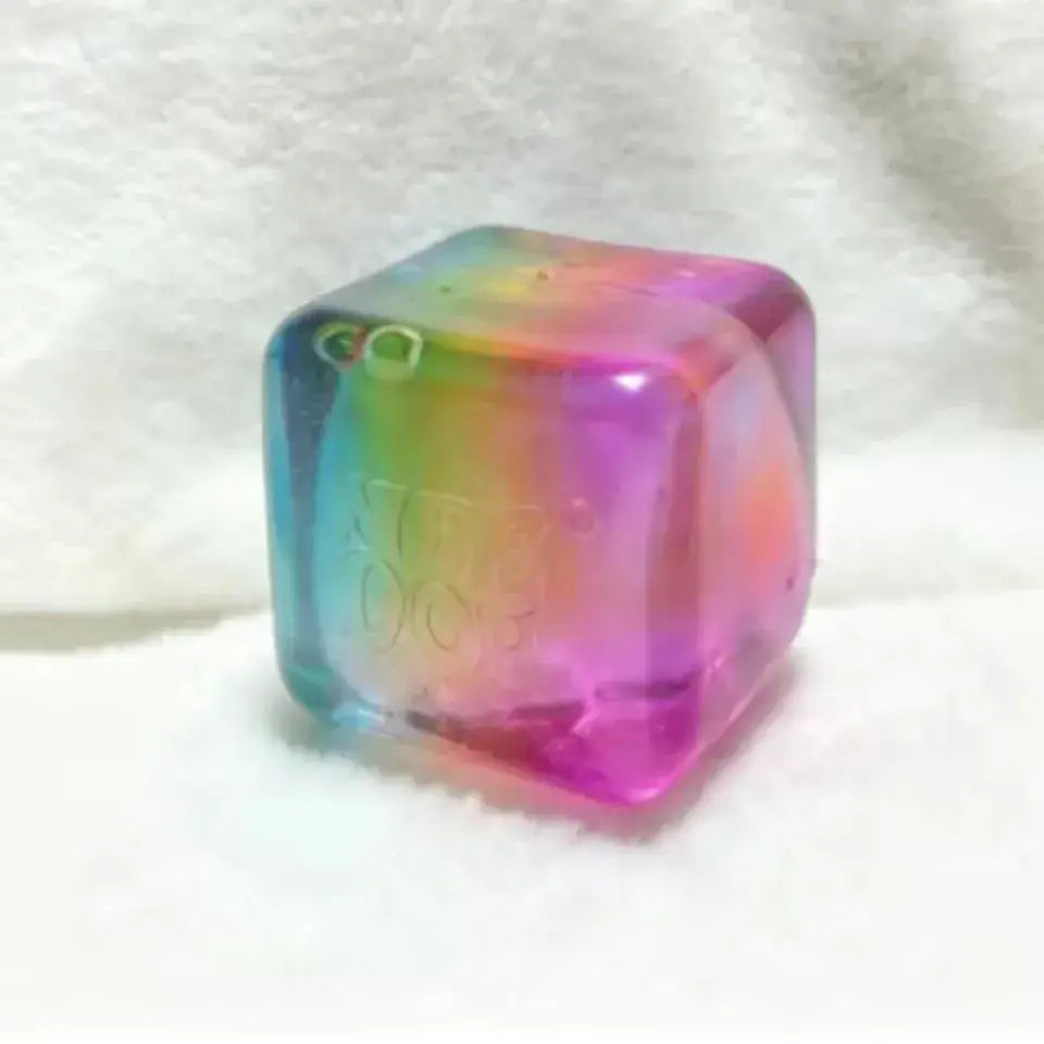 Ein transparentes, regenbogenfarbenes Needoh-Würfel-Knet- und Fidget-Spielzeug mit glatter Oberfläche und dezenten inneren Wirbeln, von der Vorderansicht aus betrachtet.