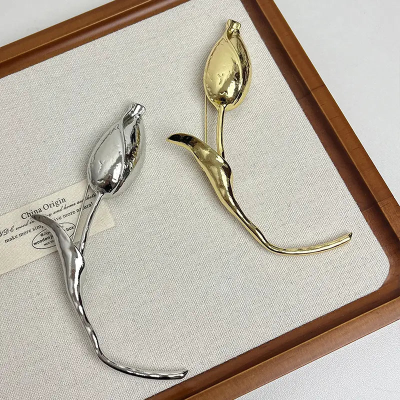 磨き上げたシルバーとゴールドトーンの仕上げによる、2点の金属製チューリップ形フローラルのブローチピン・ラペルアクセサリー。